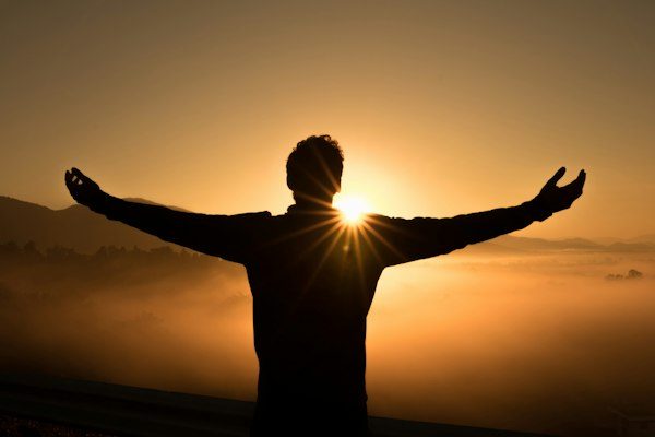 Silhouette on cliff during sunset representing inspiring connection
